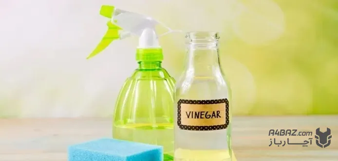 یک شیشه سرکه در کنار اسپری و اسفنج برای تمیز کردن شیرآلات
